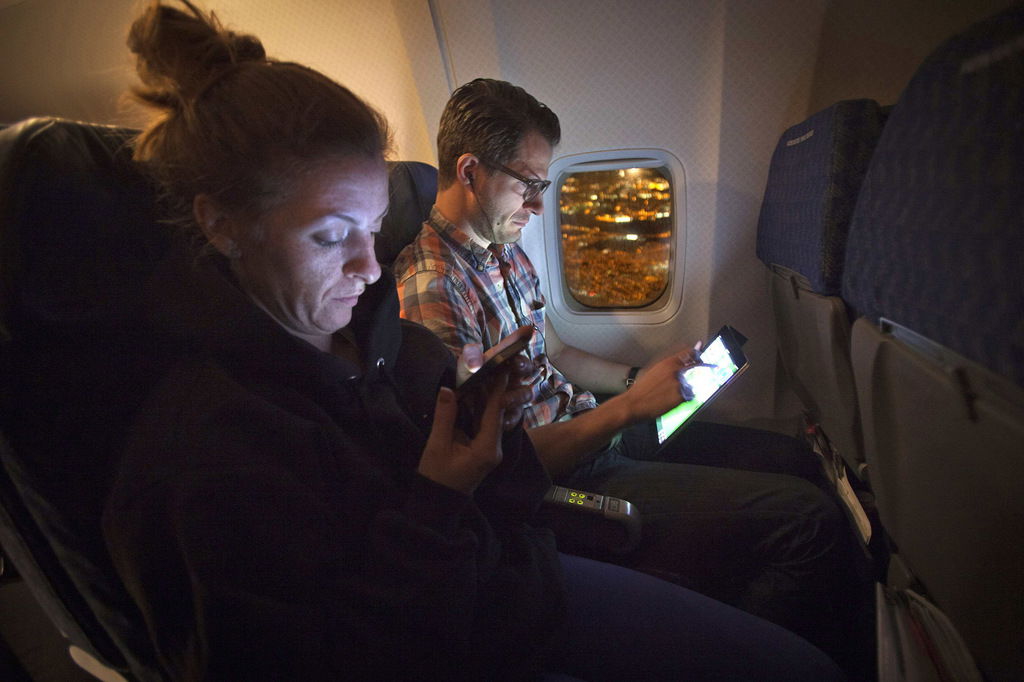 People use their smart devices on an American Airlines airplane, which is equipped with Gogo Inflight Internet service, enroute from Miami to New York